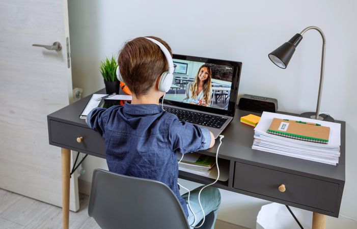 Unrecognizable boy with headphones receiving class at home with laptop from his bedroom