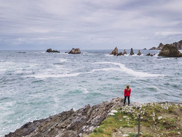 Woman standing on stony green seashore