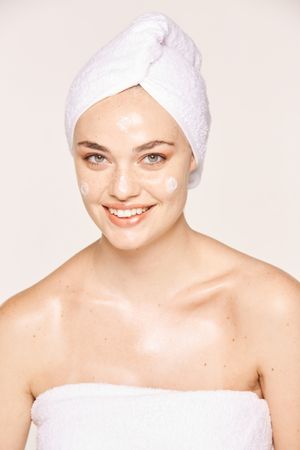 Delighted female with radiant skin applying cream