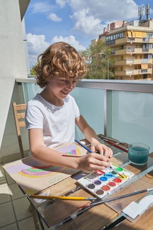 Cheerful boy painting on terrace