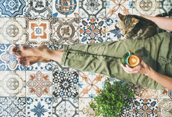 Woman on tiled terrace with coffee and cat