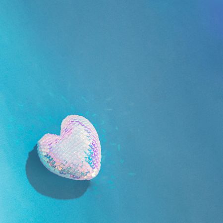 Single iridescent sequins heart on blue background