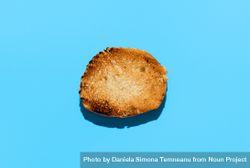 Toasted round bread slice above view on blue background 4NpRg0