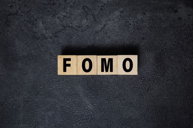 fomo symbol or fear of missing out text on wooden blocks on dark background