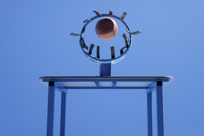 Low angle view of scoring a ball into a basketball hoop against blue sky