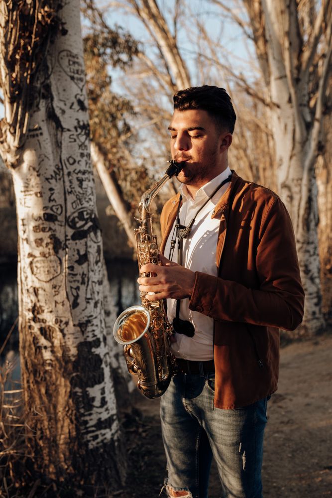 young musician playing the saxophone at sunset