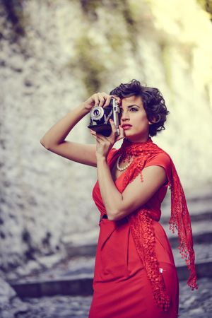 Elegant woman in dress and pearls taking a photo