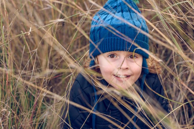 Content boy hiding in dry grass