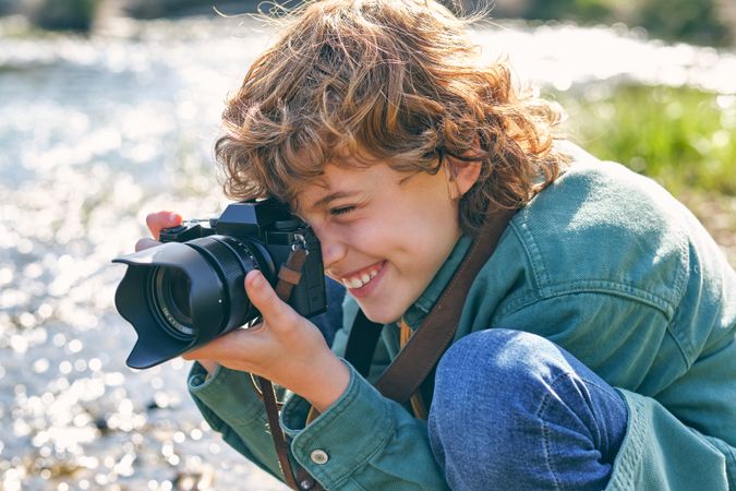Smiling boy taking photo of nature on shore