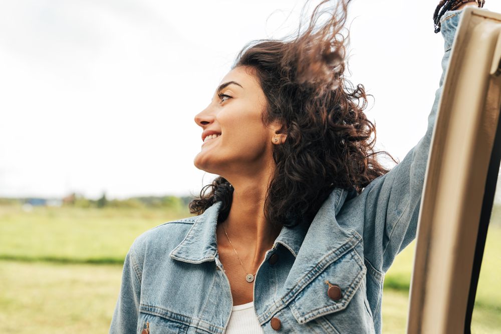 Woman looking away while leaning on car door