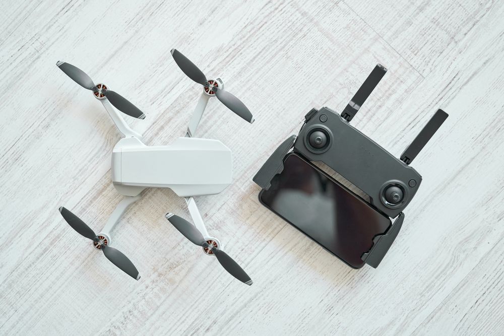 New modern drone with remote control panel placed on floor