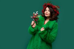 Smiling woman in green coat and red berry wreath