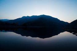 Picturesque view of water surface near amazing rock hills at sunset and blue sky