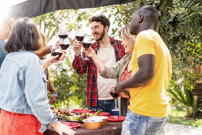 A vibrant outdoor gathering with diverse friends toasting with wine glasses