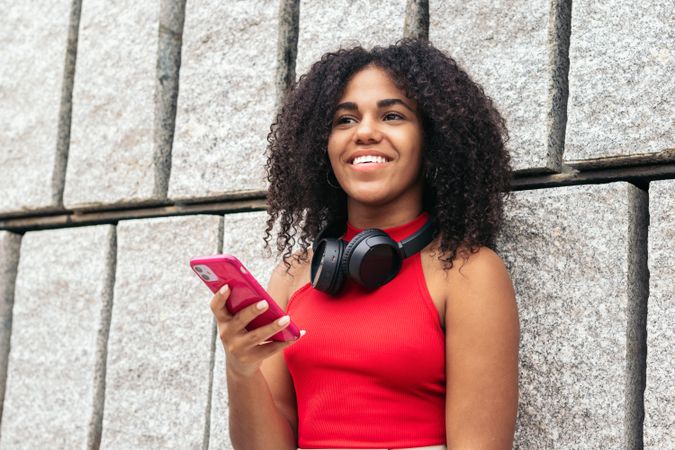 Portrait of a woman with afro hair enjoying in the city using smartphone