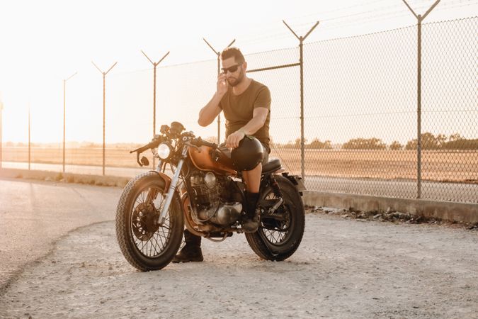 Man sitting on motorcycle and surfing mobile