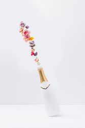 Champagne bottle popping with colorful natural spring flowers