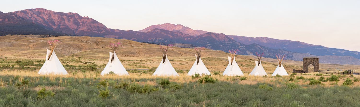 Montana, United States - August 17, 2022: Wide shot of teepees in front of mountains at sunset