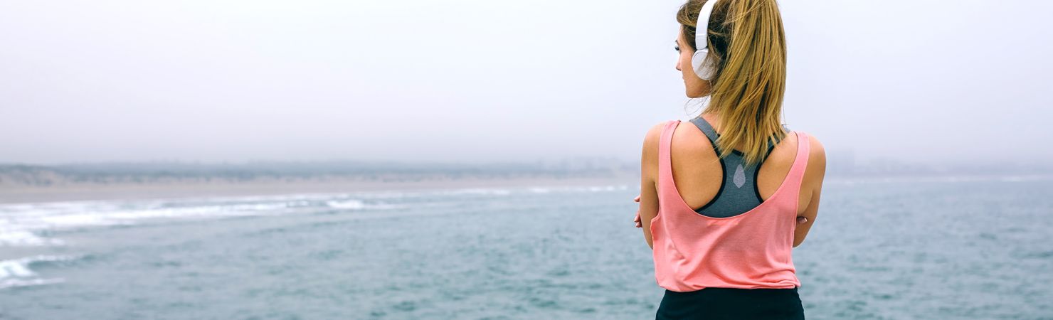 Sportswoman with headphones watching the sea