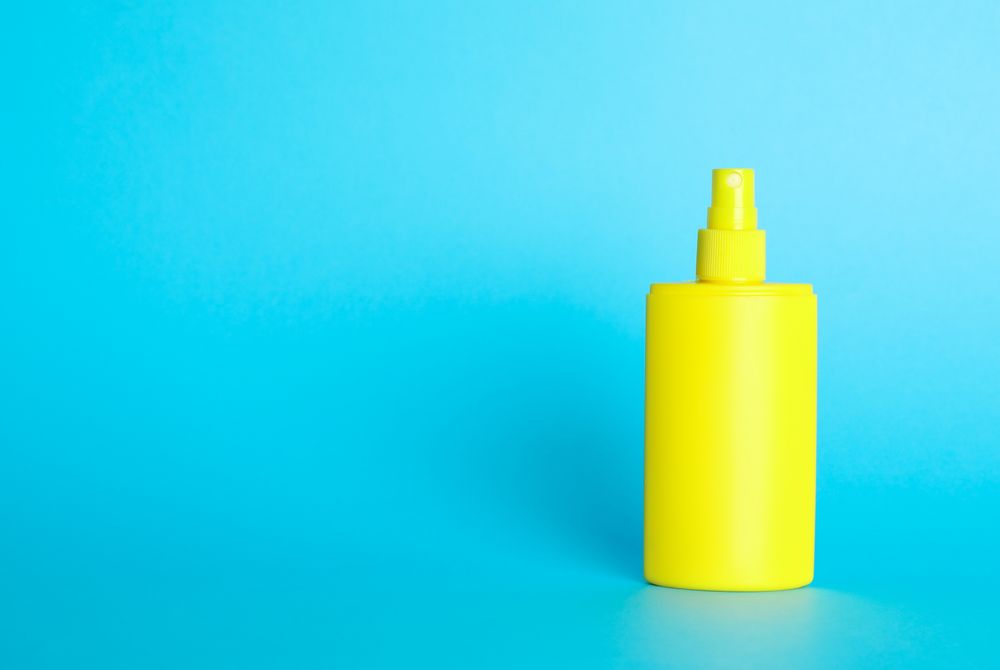 Sunscreen spray on color background, space for text