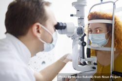 Optometrist looking into patient’s eyes with equipment 56maN0