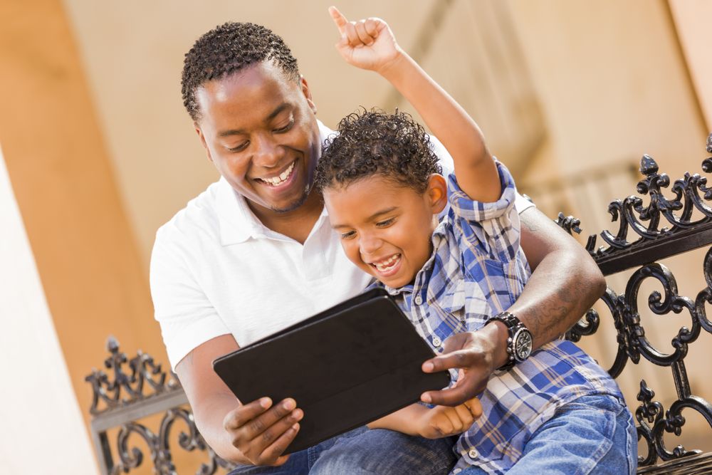 Happy Father and Son Using Tablet On Balcony