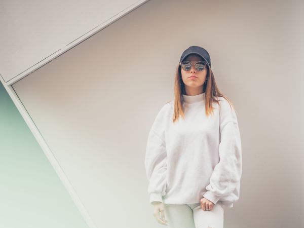 Young woman with glasses standing against wall