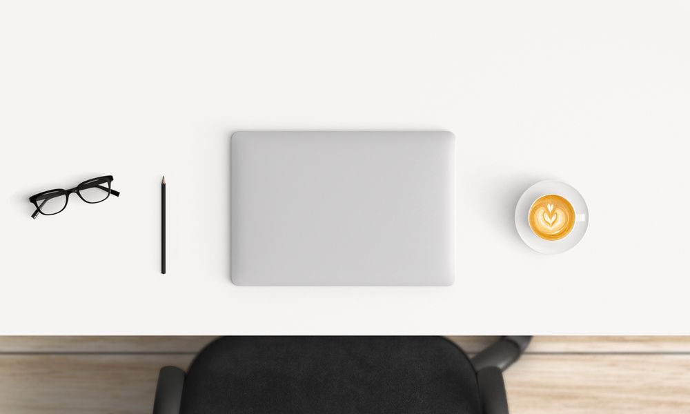Modern workplace with laptop, coffee cup and notebook copy space on table background. Top view. Flat lay style.