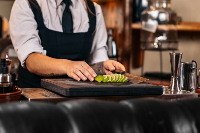 Close-up of a female bartender cutting limes to prepare cocktails