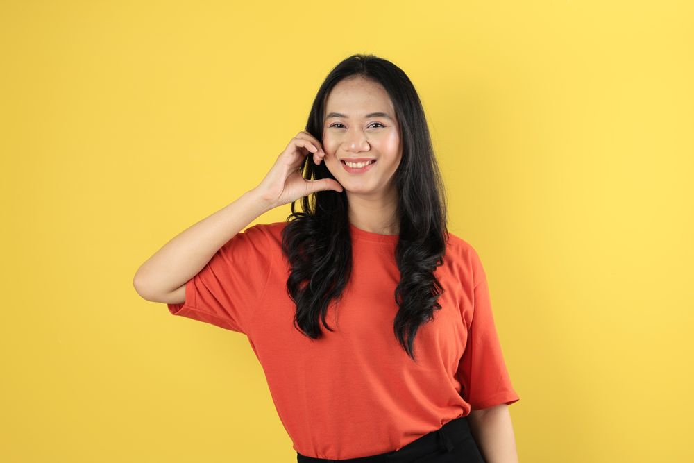Portrait of Young Asian Indonesian Female making Love Heart Sign on Her Cheek