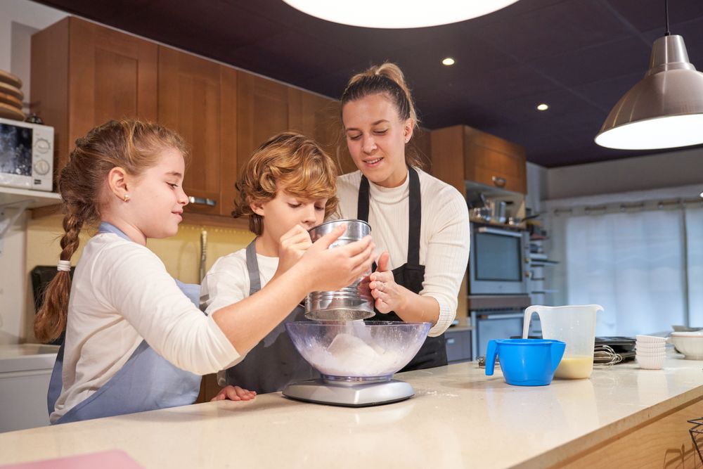 Mother with kids sifting flour for dough in bowl