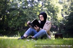 Calm woman in head scarf reading in the park 0gpMl5
