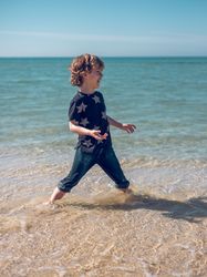 Happy kid standing in water on shore