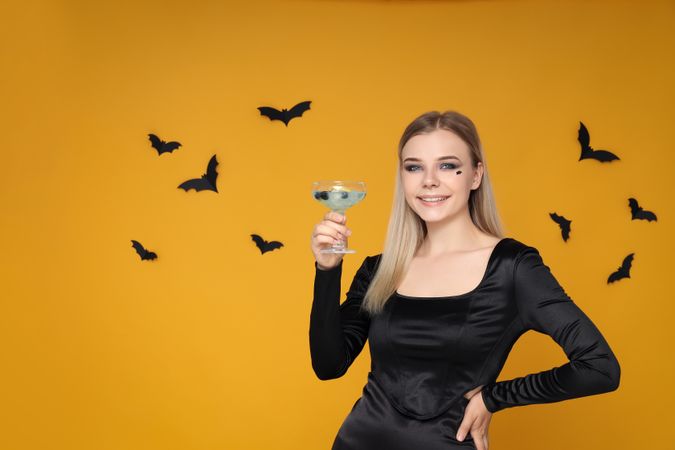 Concept of Halloween, young woman on yellow background