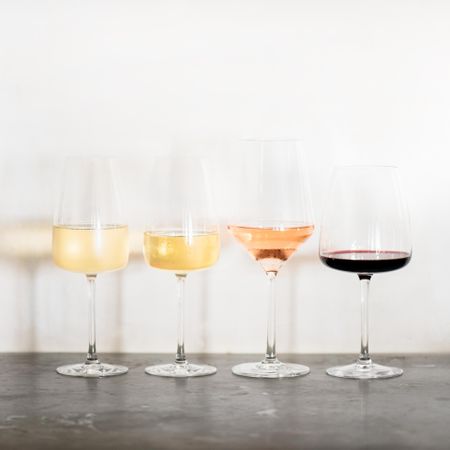 Wine flight of 4 types of wine, from light to dark, in different shaped glassware, square crop