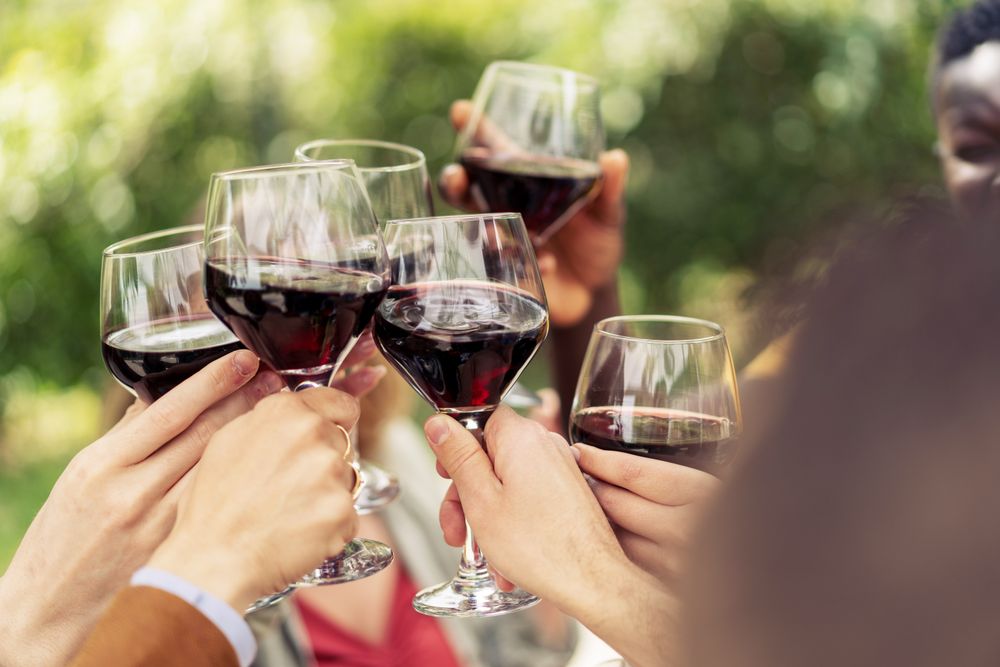 Close-up of friends toasting with red wine in an outdoor celebration