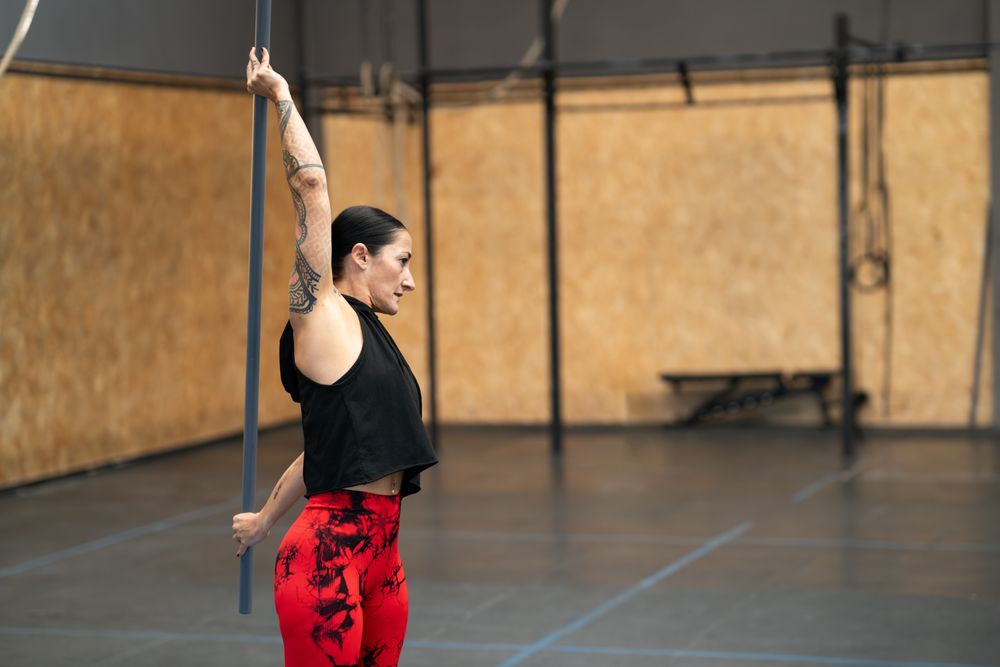 Fit woman stretching with a bar in a gym