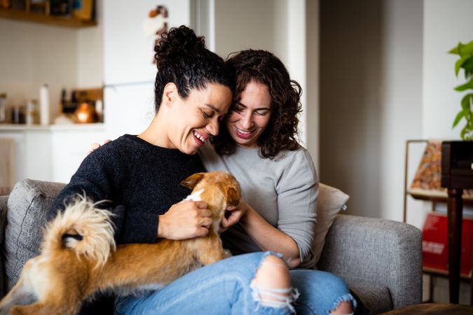 Female couple relaxing at home on sofa with their dog