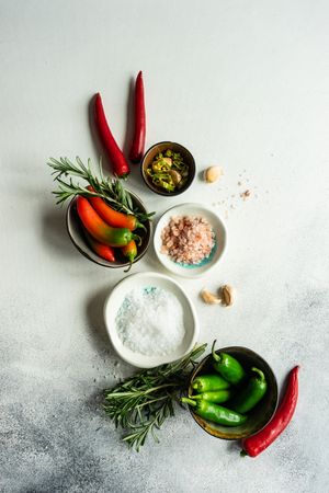 Top view of marble counter with peppers, herbs and salt