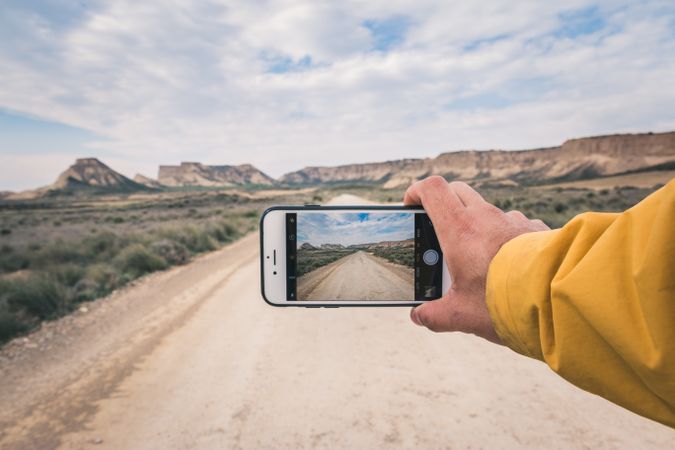 Person taking picture of empty road and desert landscape