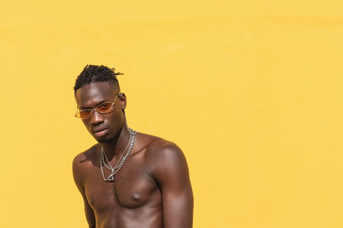 Serious Black man in trendy sunglasses near wall