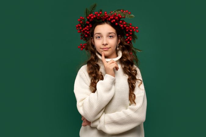 Girl wearing red berry wreath, posing with curious expression