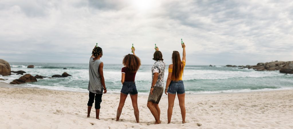 Group of friends having party celebrating and drinking at the beach