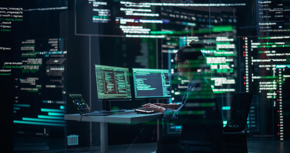 Female Programmer Working in Monitoring Control Room, Surrounded by Big Screens Displaying Lines of Programming Language Code.