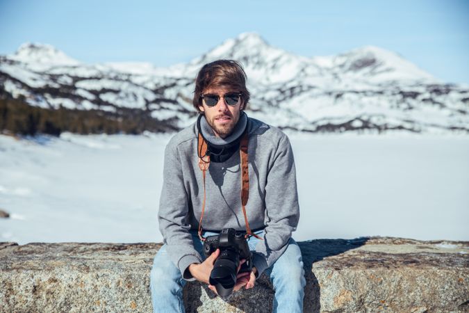 Man with camera near hill in winter