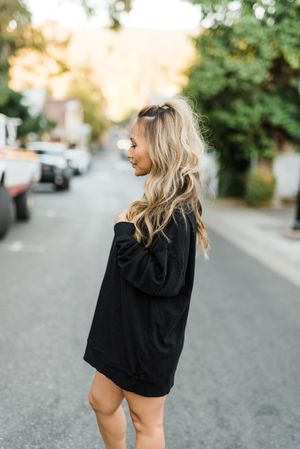 Side view of woman with blonde wearing dark sweater standing on road