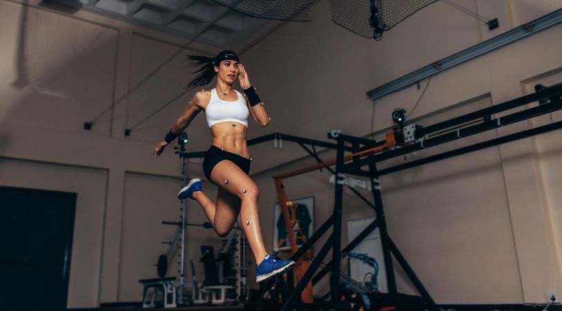 Female athlete with motion capture sensors on her body running in biomechanics lab
