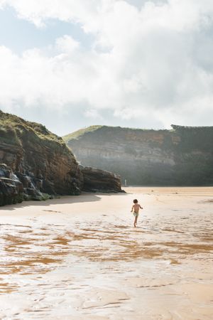 Boy kid walking on wet sunny beach