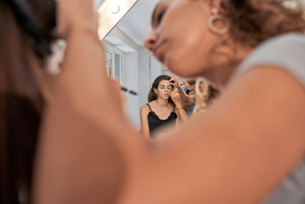 Focused woman applying eyeshadow on woman near mirror