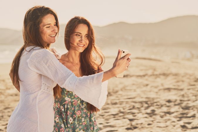 Smiling women making selfie on beach